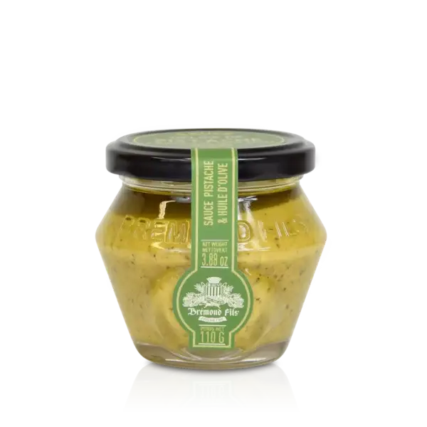 Glasskrukke med grønn etikett som inneholder pistasjpesto med olivenolje